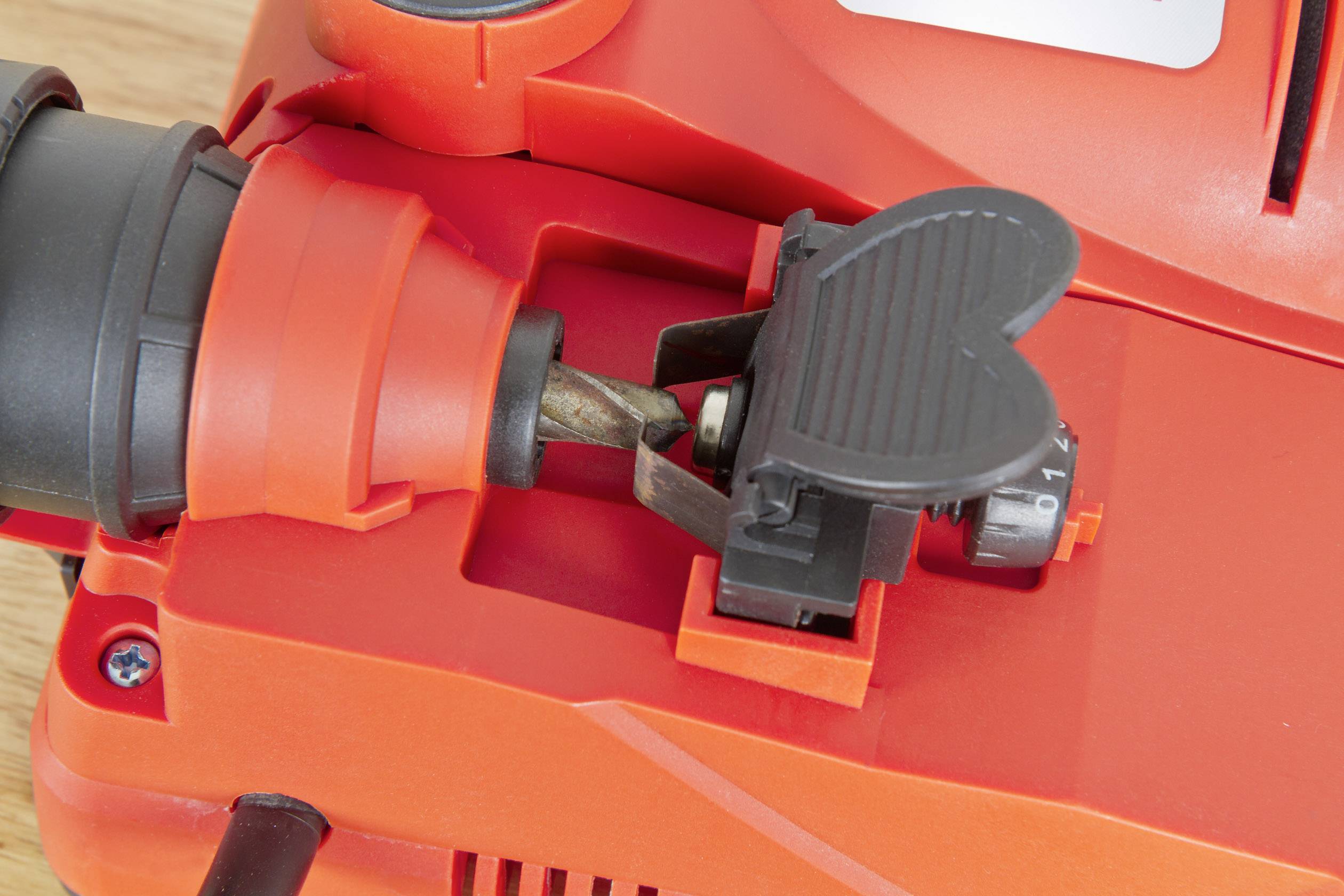 Een oranje boor met een boorbit geplaatst op een werkbank. De boor is geschikt voor hout- of metaalbewerkingen.