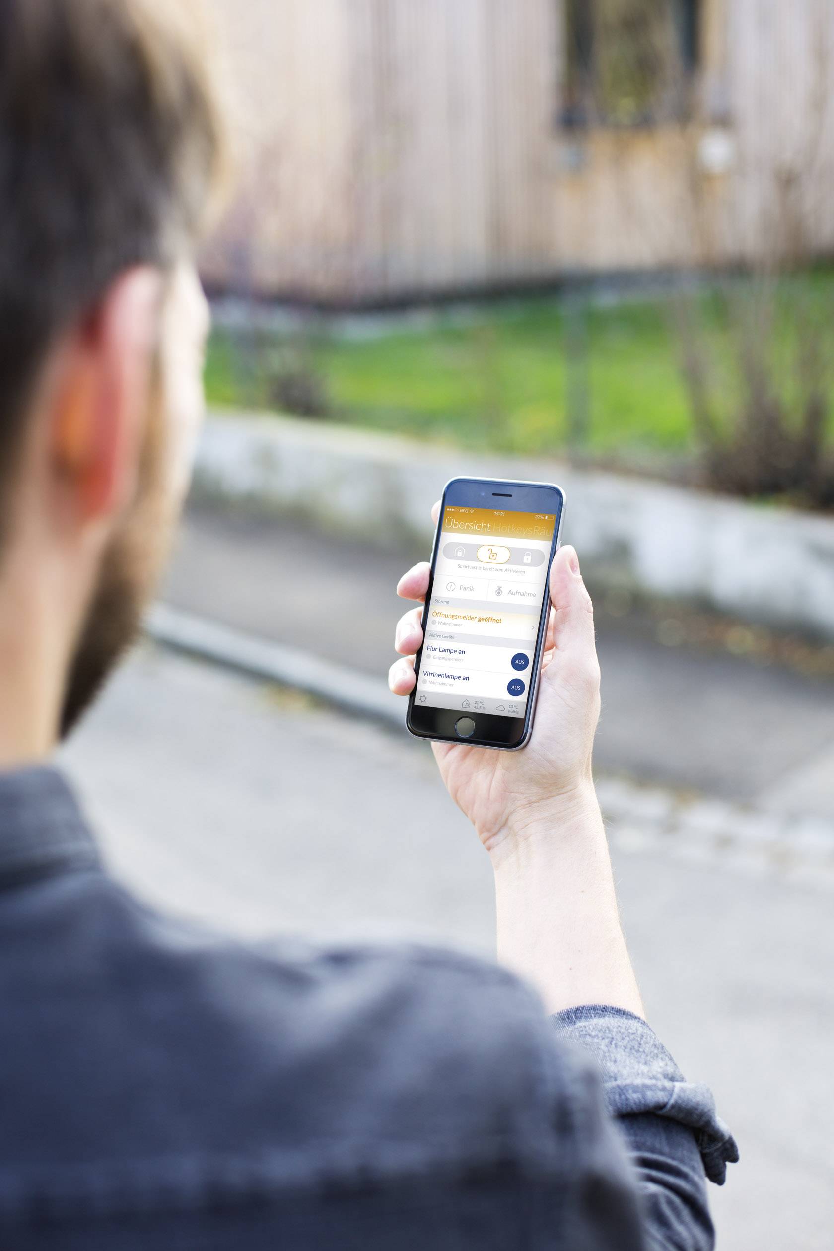 Een man houdt een smartphone in zijn hand waarop een app met verschillende instellingen wordt weergegeven. Hij staat buiten.