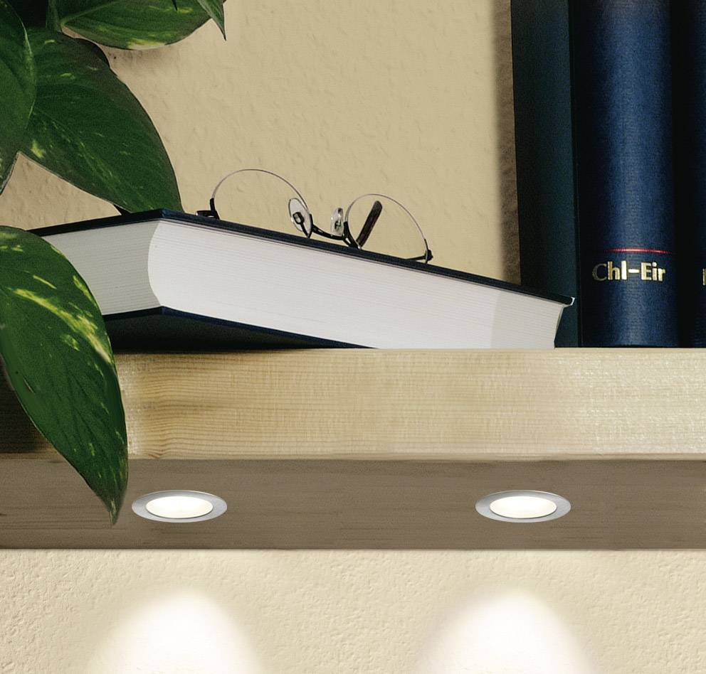 Een boek ligt op een plank tussen planten. Bovenaan zijn delen van een boekrug zichtbaar. Onderaan zijn ingebouwde verlichting.