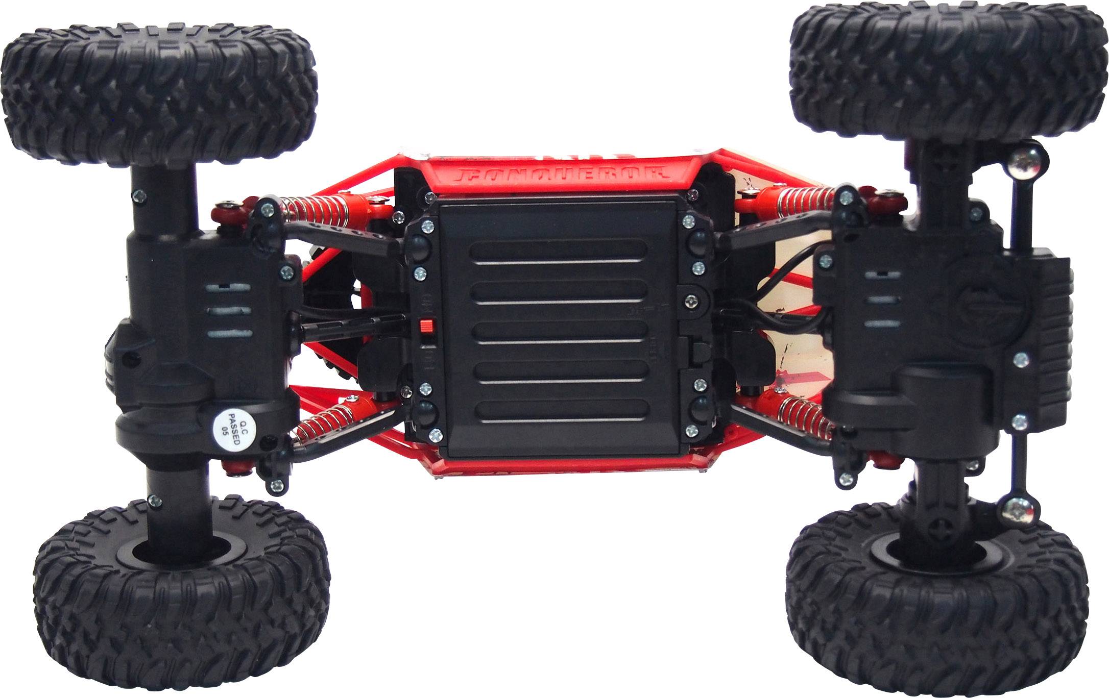 Speelgoedauto, gefotografeerd van onderen, toont een robuust chassis met grote, terreinvaardige banden en schokdempende ophanging.