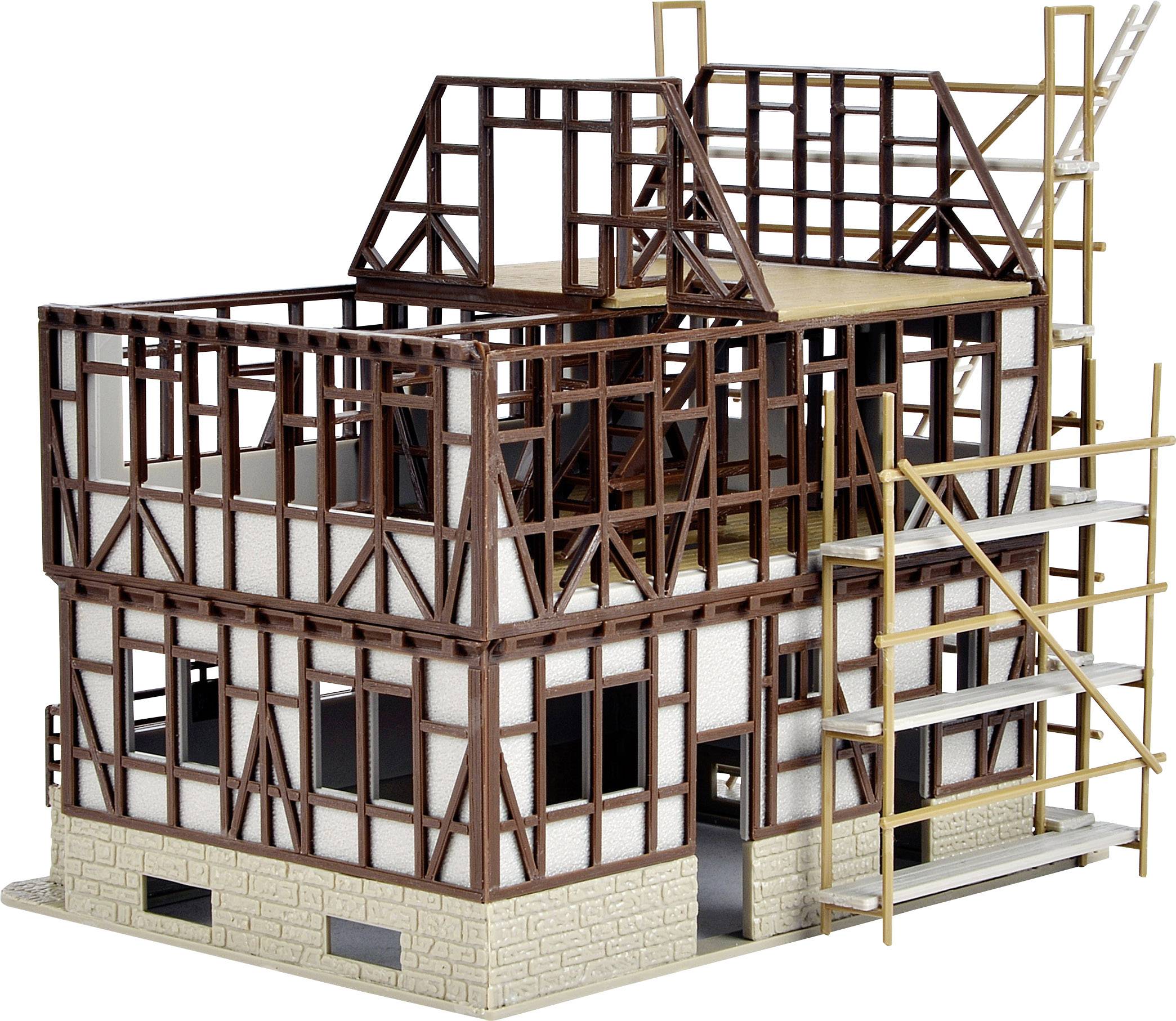 Een model van een vakwerkwoning in aanbouw met zichtbare houten balken en een steiger rond het gebouw.