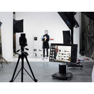 Een fotostudio-opname: Een persoon staat voor een rek met camera's en accessoires. Op de voorgrond zijn camera's en een computerscherm zichtbaar.