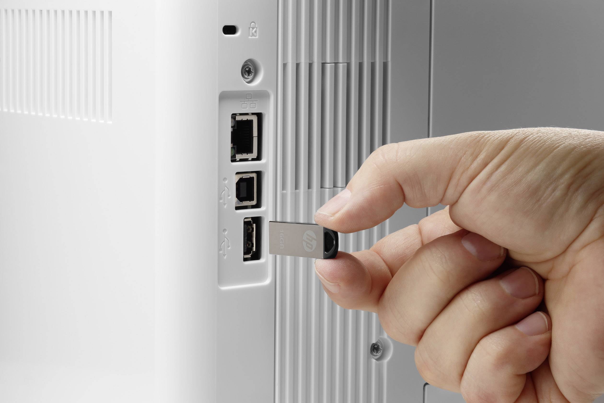 Hand steekt USB-stick in een USB-poort van een elektronisch apparaat.