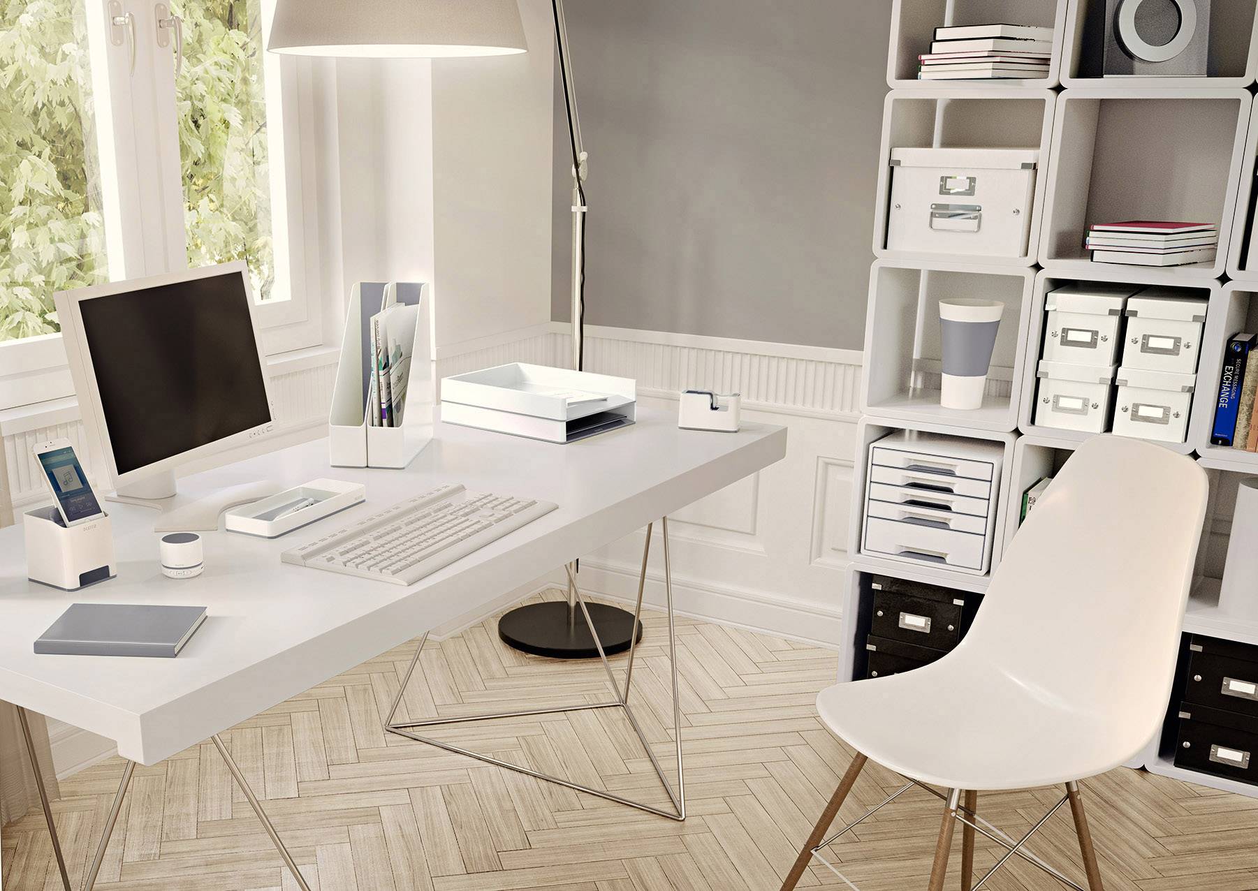Moderne, goed georganiseerde werkplek met een bureau, monitor, toetsenbord, laptop en planken vol mappen en dozen naast een raam.