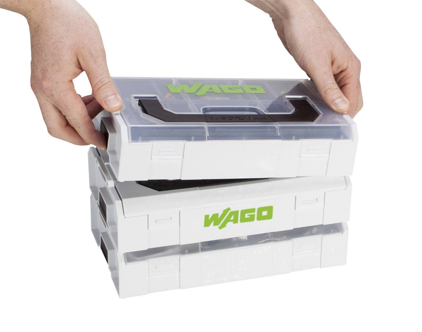 Twee handen stapelen drie witte kunststof dozen met het groene 'WAGO' logo op elkaar.