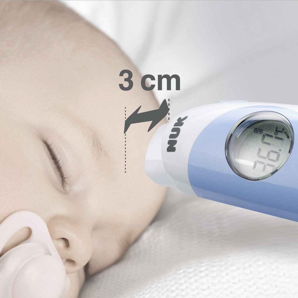 Een digitale thermometer meet de temperatuur van een slapende baby op 3 cm afstand en geeft 36,7°C aan.