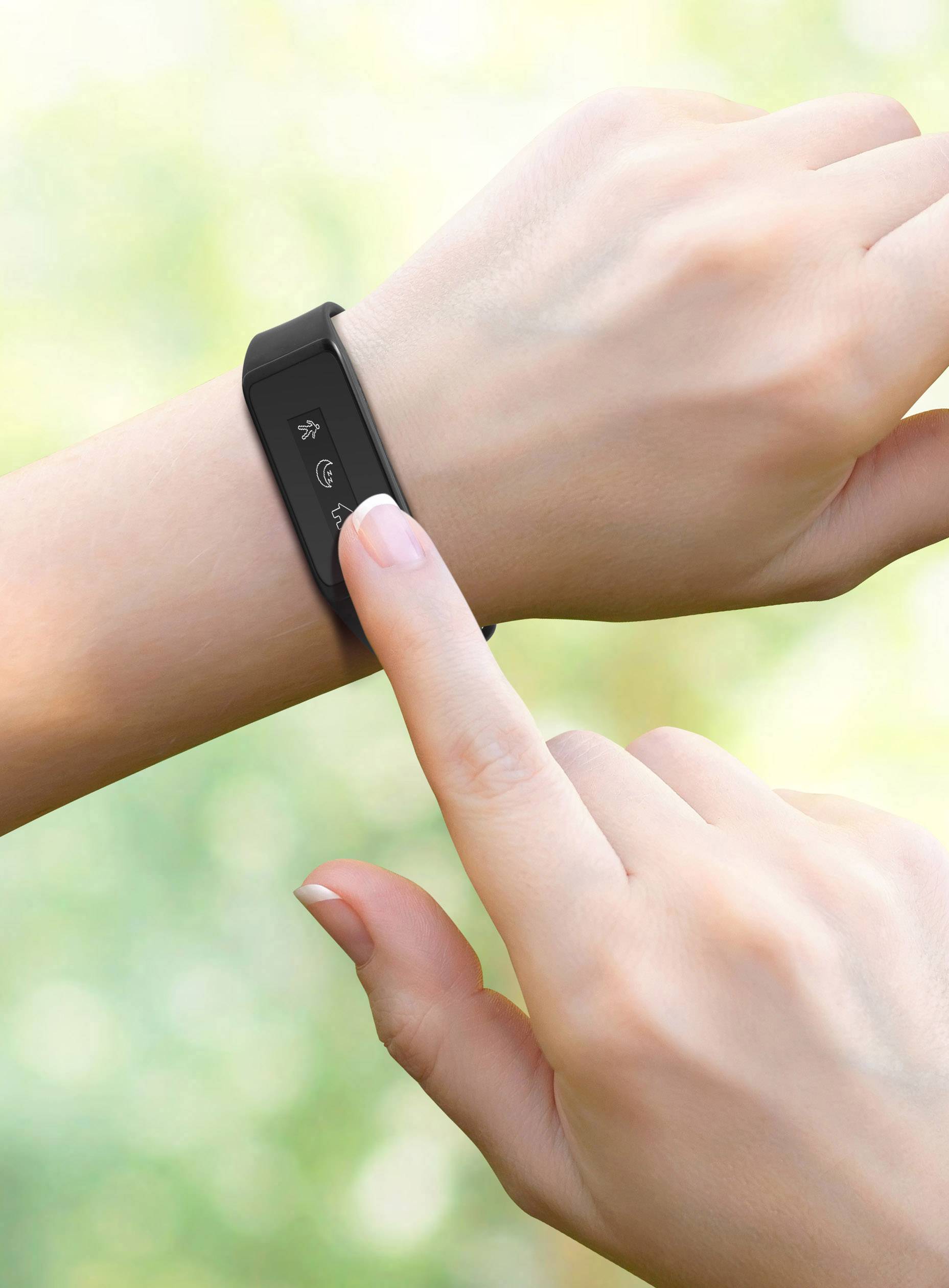 Een persoon tikt op het display van een zwarte fitness-tracker aan de pols om een functie te activeren. Achtergrond wazig.