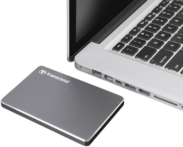 Externe harde schijf naast een opengeslagen laptop op een bureau. De laptop is gedeeltelijk zichtbaar.
