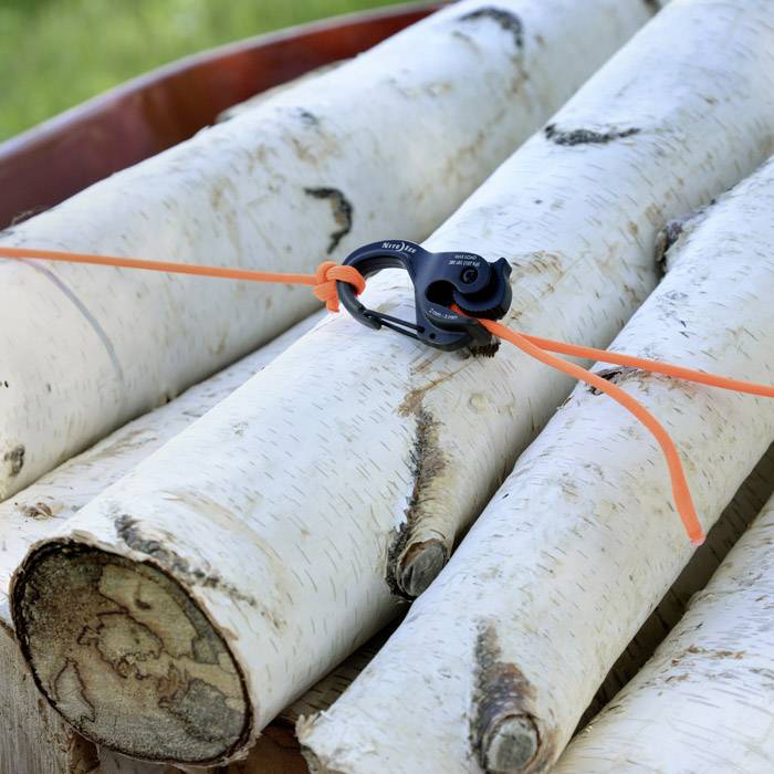 Een hoop witte berkenstammen, vastgemaakt met oranje touw en een zwarte haak.