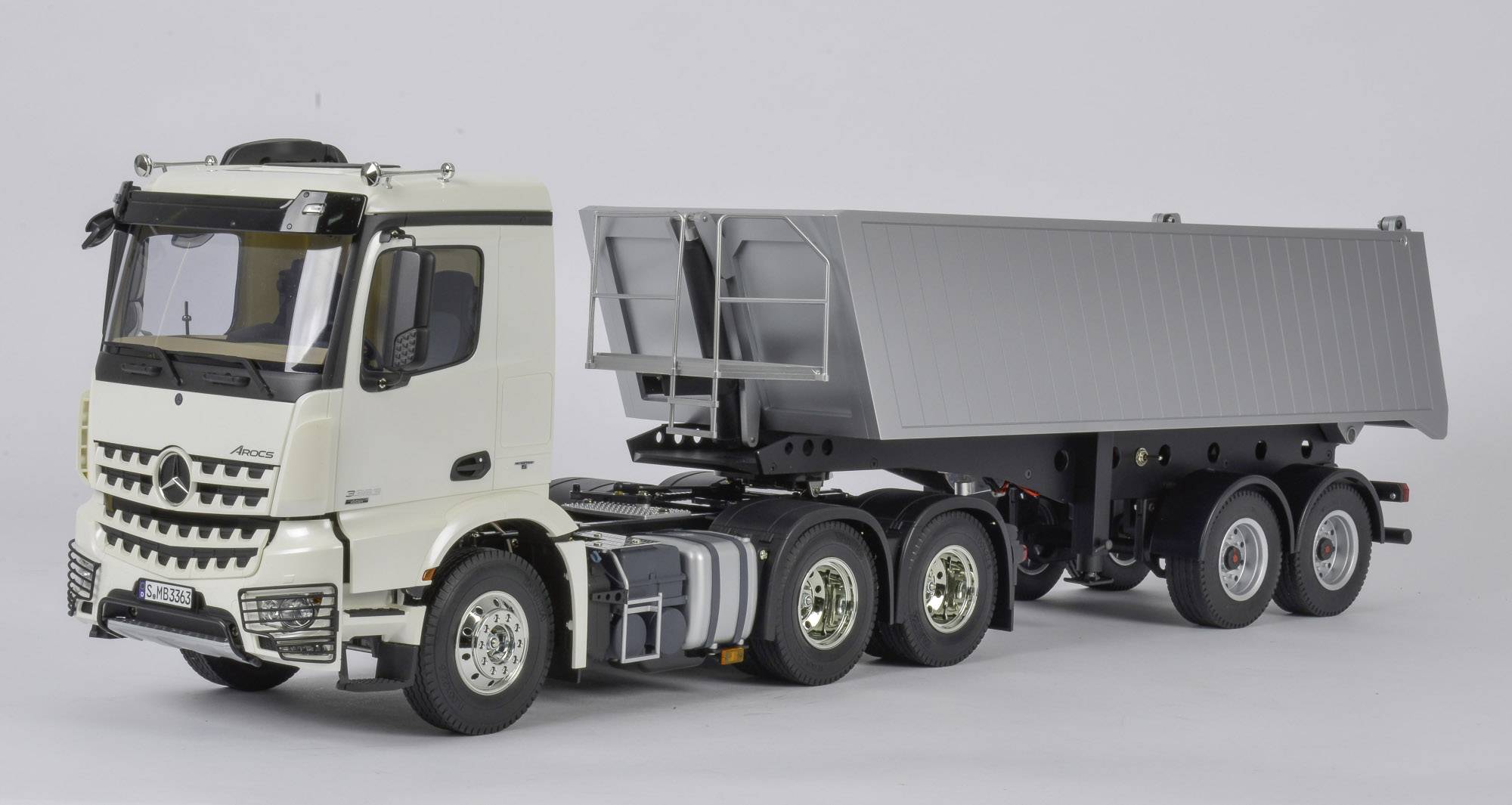 Vrachtwagen-model met kieptrailer in witte kleur, zijaanzicht. De vrachtwagen toont gedetailleerde kenmerken en het ontwerp van een vrachtwagen.