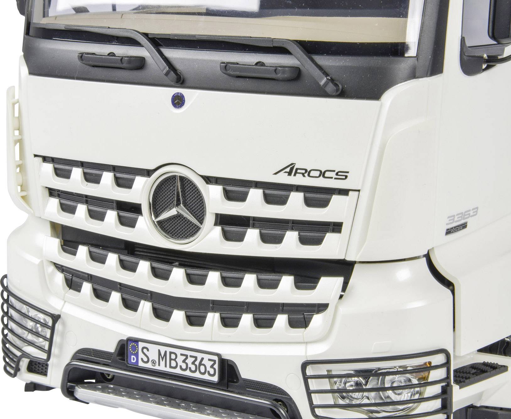 Close-up van een witte vrachtwagen van het merk 'Arocs', met een opvallende radiatorgrille en logo in het midden, kenteken 'S-MB3363'.