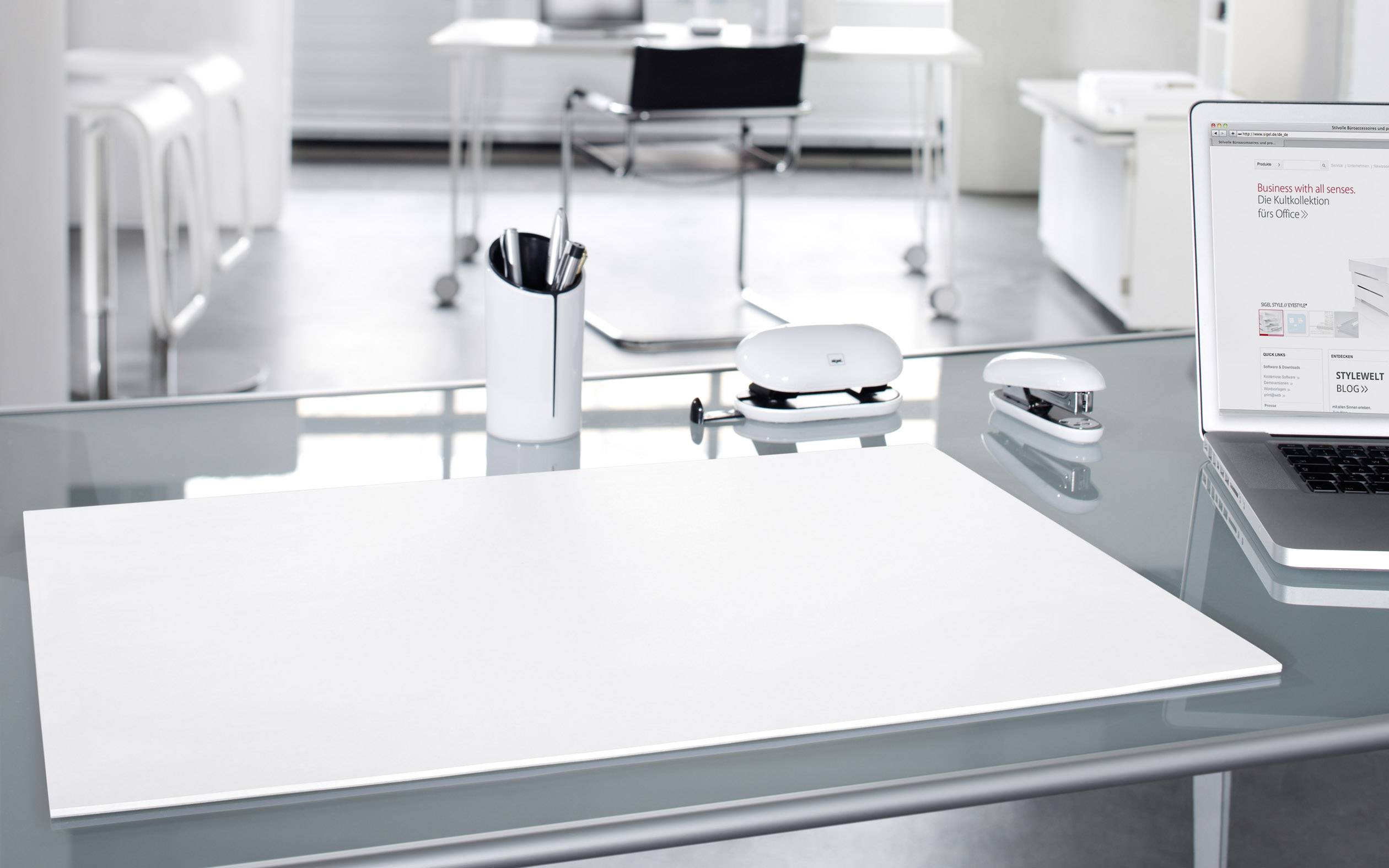 Moderne kantoorruimte met een leeg bureau, laptop, pennenbak en decoratieve elementen op de achtergrond.