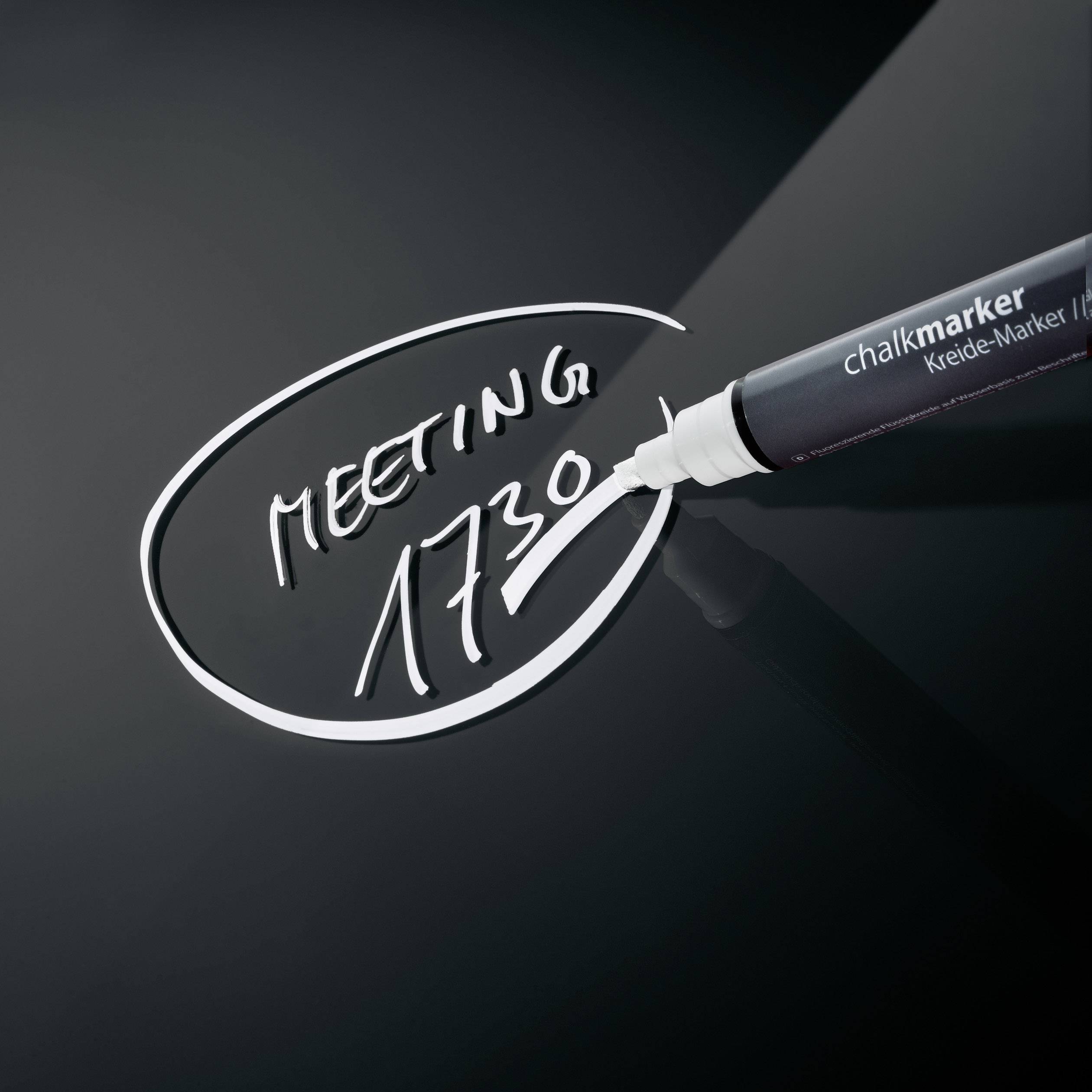 Een krijtmarker schrijft 'MEETING 17:30' op een zwart schoolbord.