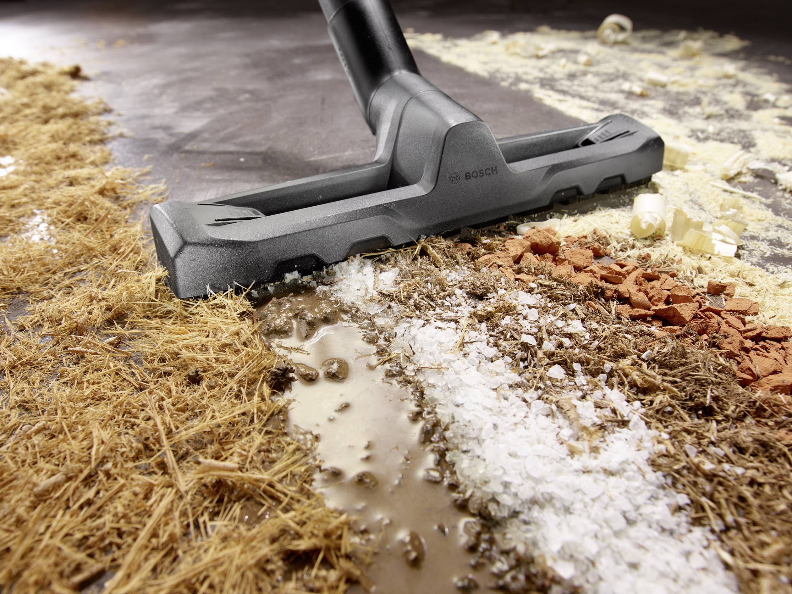 Een stofzuiger zuigt een mengsel van vuil en verschillende deeltjes van een vloer.