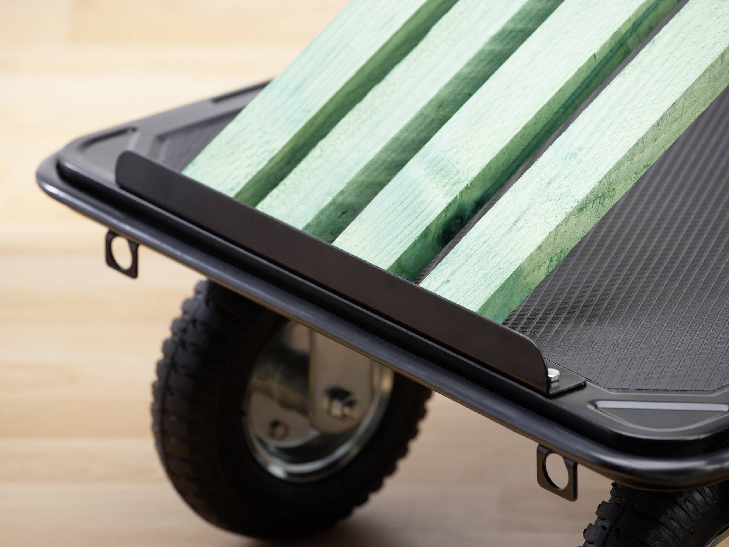 Transportwagen met zwarte wielen en groene houten lading op houten vloer.