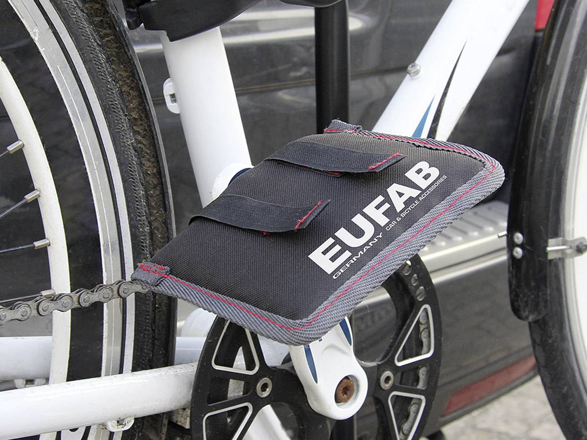 Zwart beschermend kussen met het opschrift 'EUFAB' op een wit fietsframe, bevestigd in het kettinggedeelte, beschermt tegen vuil.