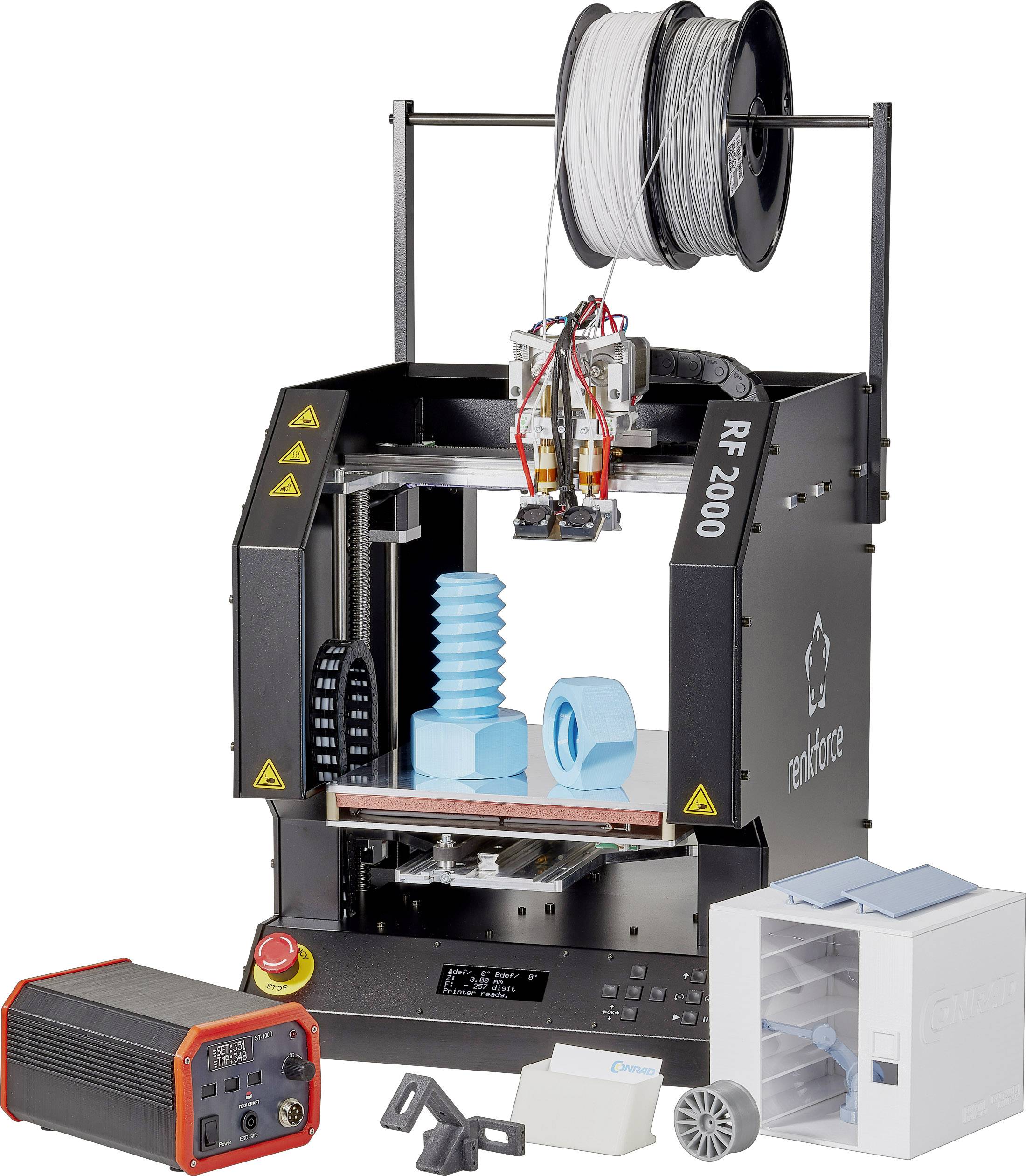 Een 3D-printer met twee printkoppen drukt blauwe modellen. Bovenaan zijn twee filamentrollen gemonteerd. Links en rechts zijn accessoireonderdelen zichtbaar.