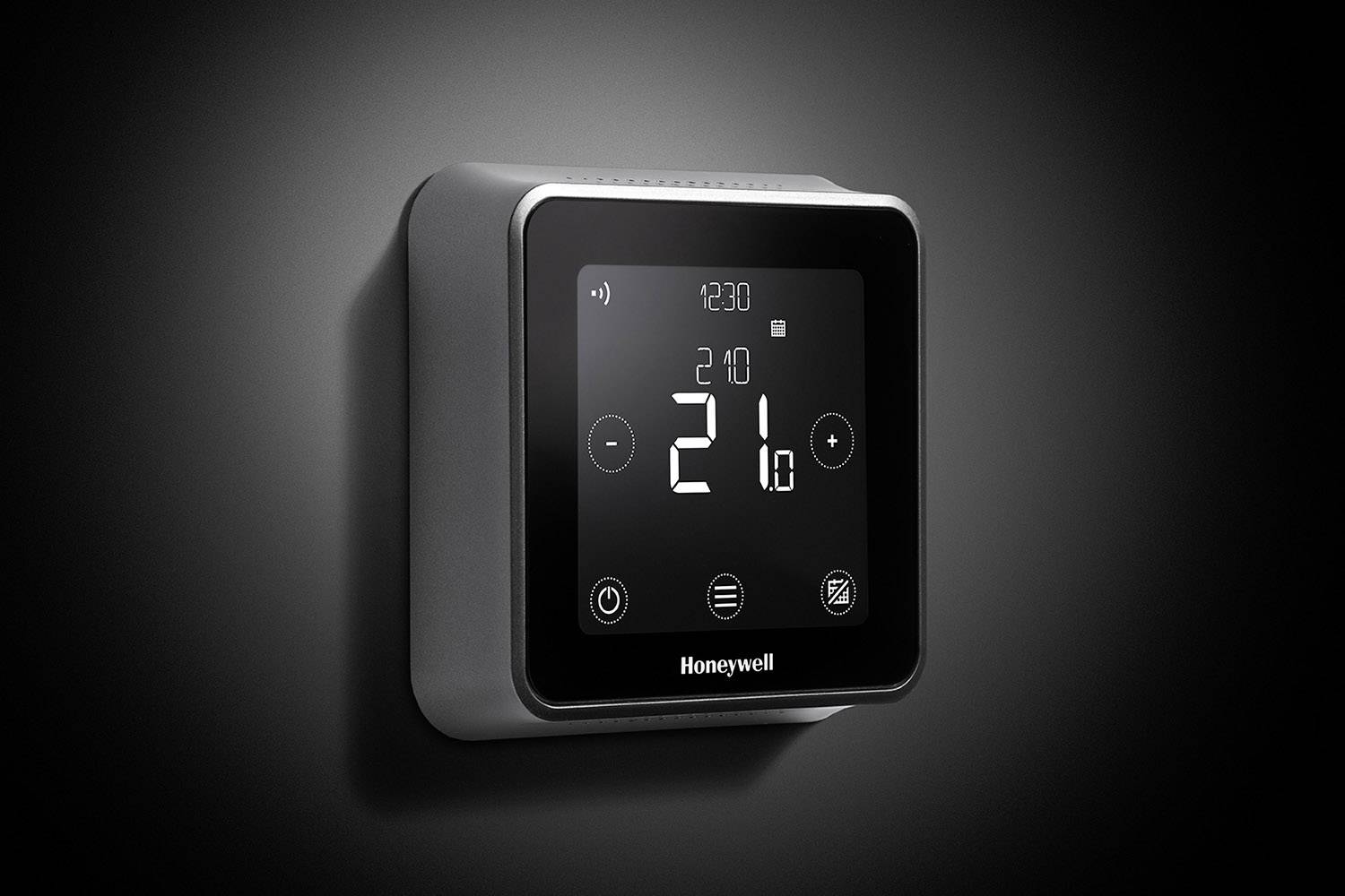 Een digitale thermostaat aan de muur toont een temperatuur van 21 graden Celsius. Hij heeft een moderne, vierkante vorm.