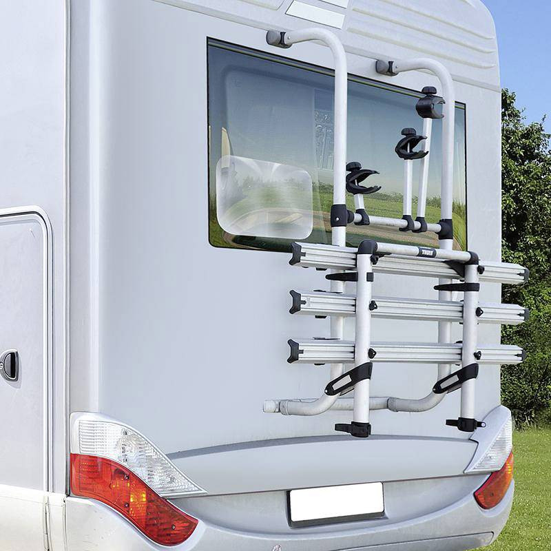 Camper-achterkant met gemonteerde fietsendrager, omgeven door groen gazon.