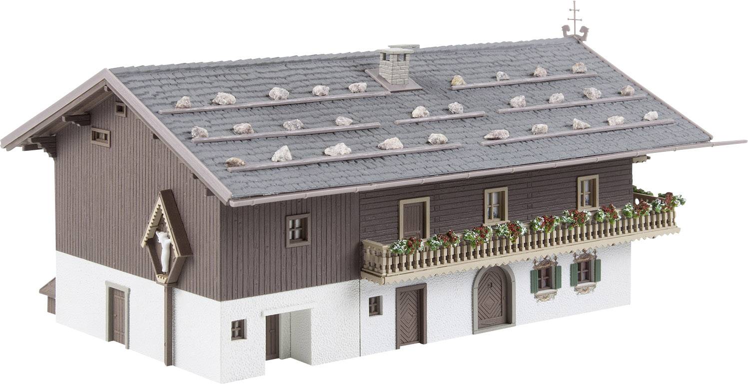 Een miniatuur van een tweeverdiepings boerenhuis met een bruin houten gebouw, een balkon met bloembakken en een gedetailleerd dakbeschot.
