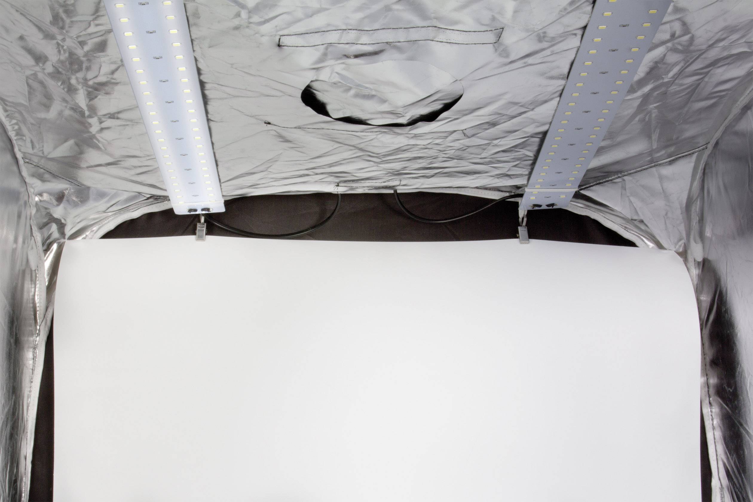 Verlicht fotostudiotent met een witte achtergrond en twee LED-balken bovenaan bevestigd voor gelijkmatige verlichting.