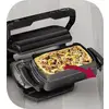 Een elektrische grill met een opengeslagen klep toont een pizza aan de binnenkant. Een rode pijl wijst naar de pizza.