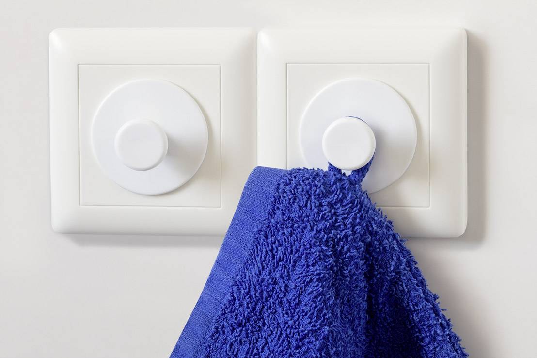 Twee draaiknoppen aan de muur met een blauwe handdoek die aan een van de schakelaars hangt.