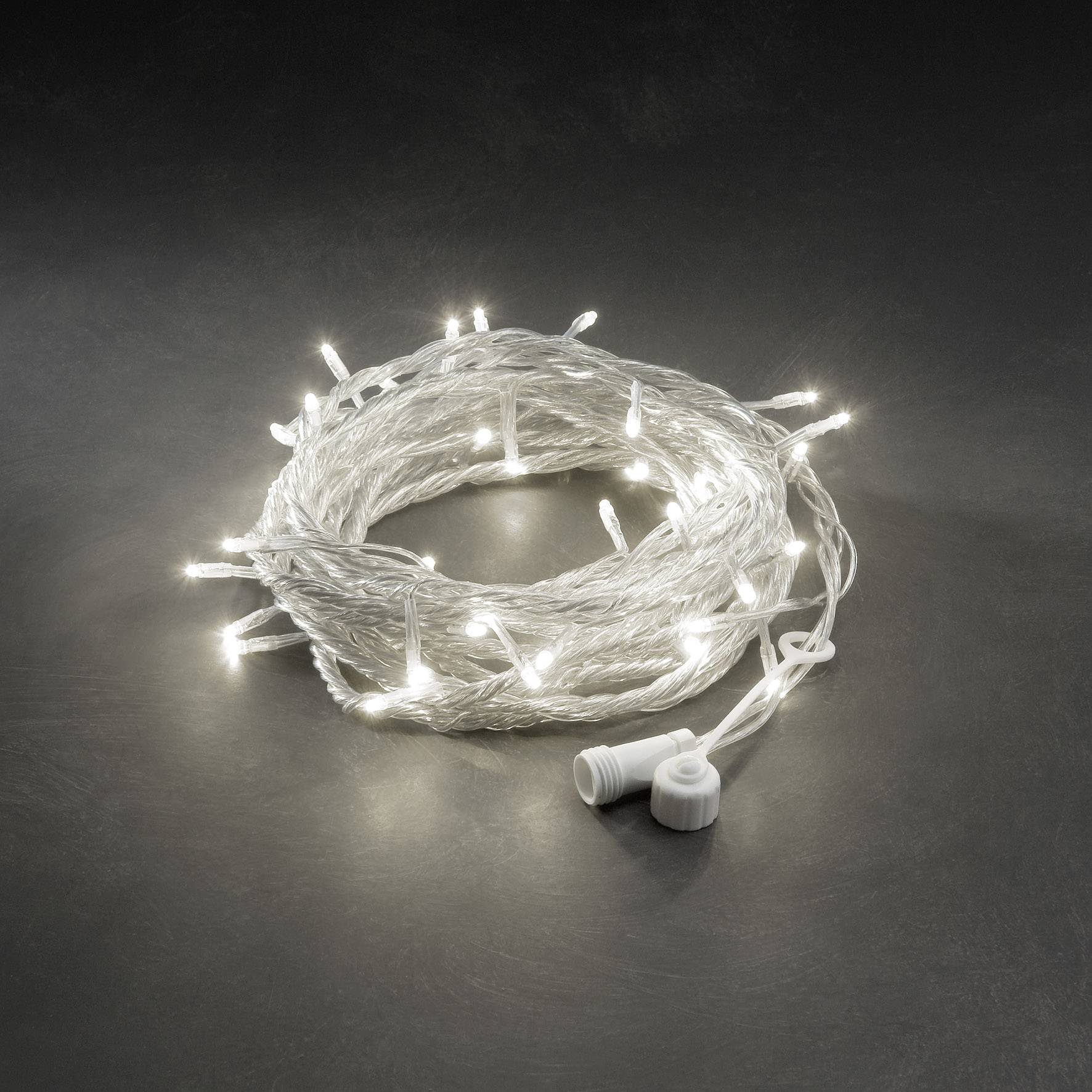 Een bundel witte LED-lichtslingers ligt opgerold op een donkere ondergrond. De lichtjes schijnen subtiel, een stekkersaansluiting is zichtbaar.