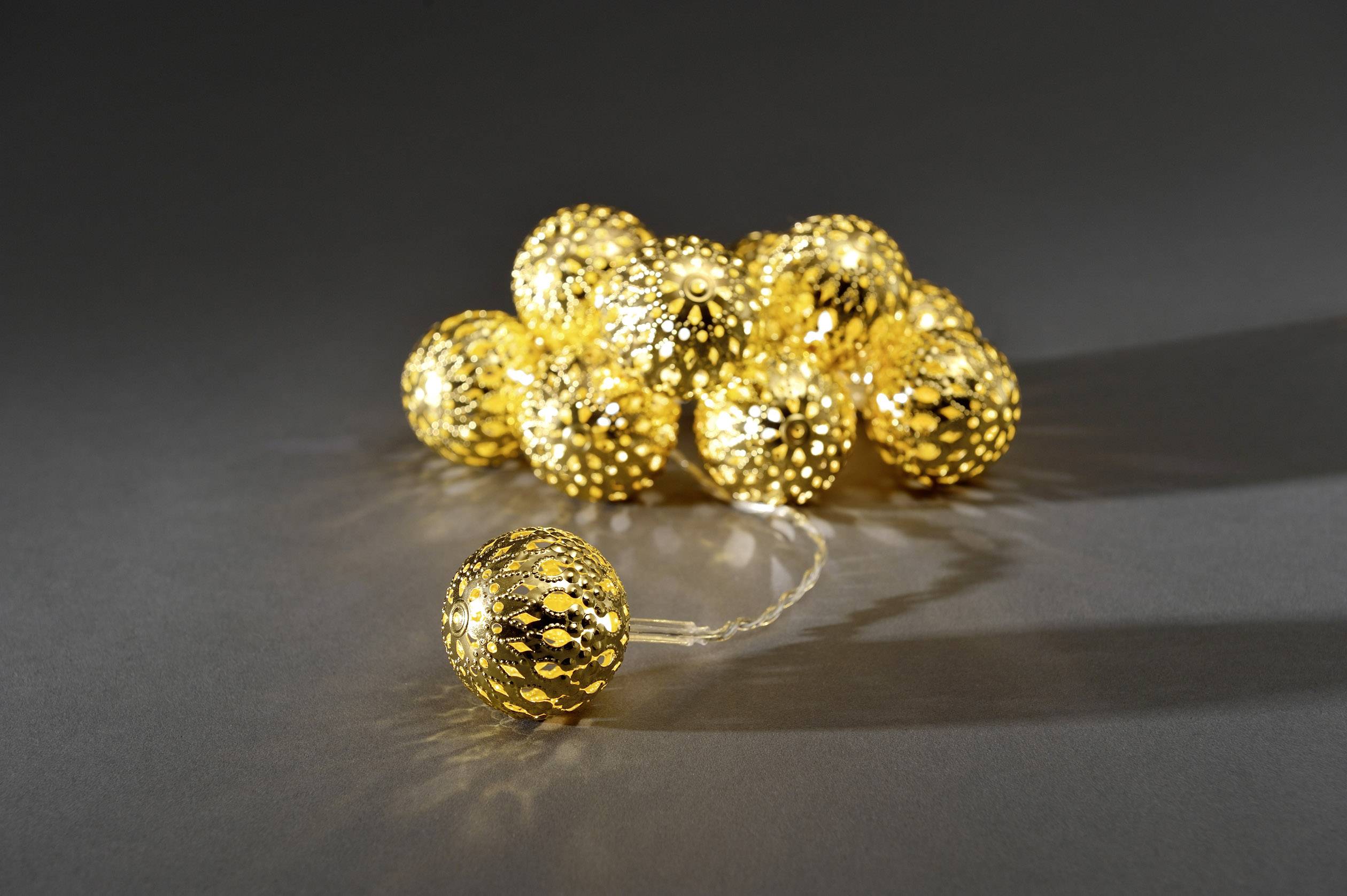 Een lichtsnoer met gouden ballen op een donkere achtergrond. De ballen zijn stralend en werpen gedetailleerde patronen.