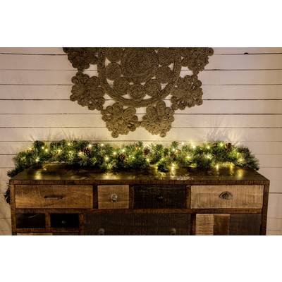 Houten dressoir met laden, versierd met dennenslingers en lichten. Achtergrond van witte houten muren met wanddecoratie.