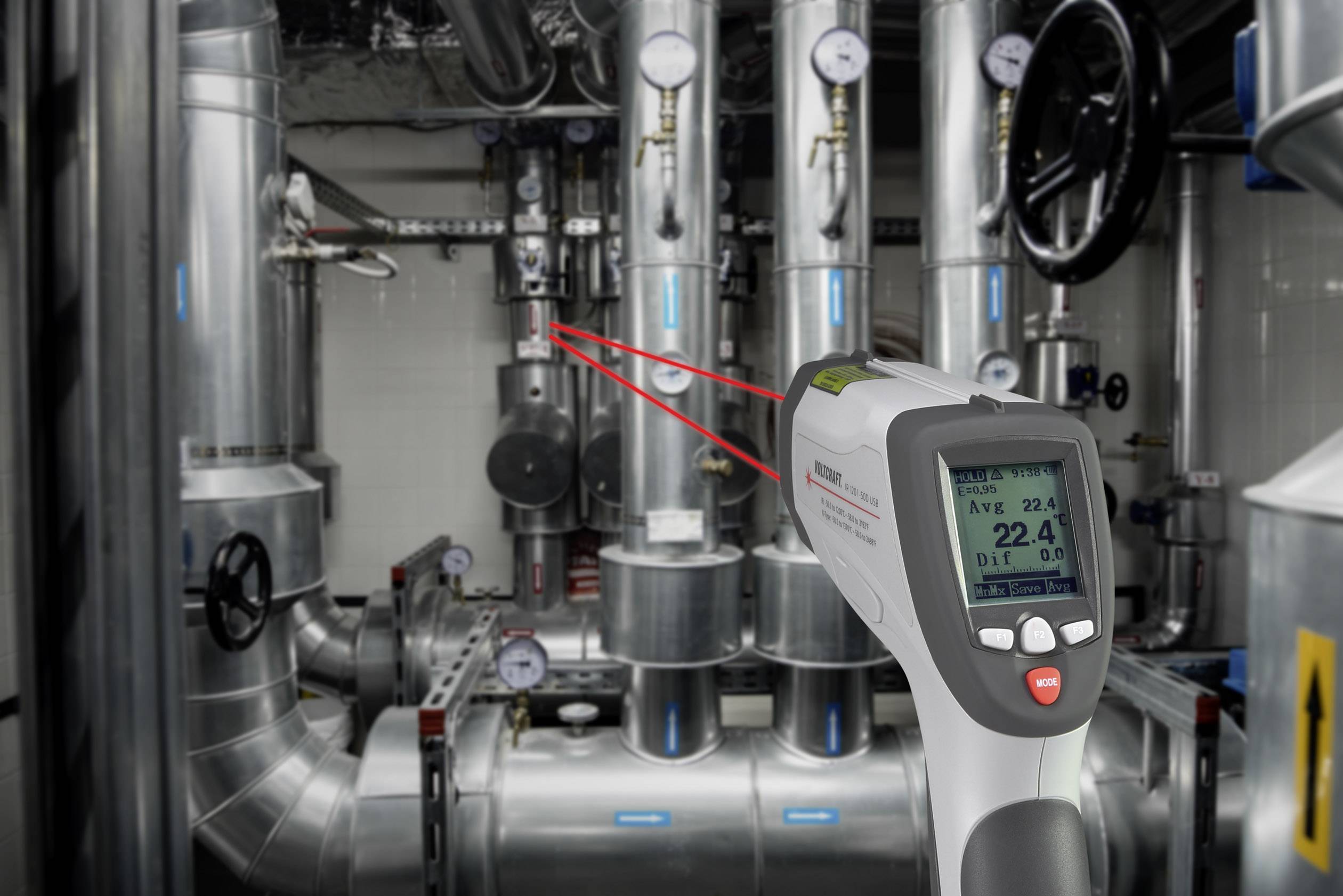 Een digitale infrarood-thermometer meet de temperatuur van buizen in een industriële installatie. Het display toont '22,4 °C'.