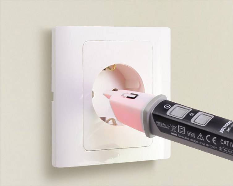 Een spanningzoeker wordt in een wit stopcontact gestoken. Het apparaat licht rood op, wat wijst op spanning in het stopcontact.