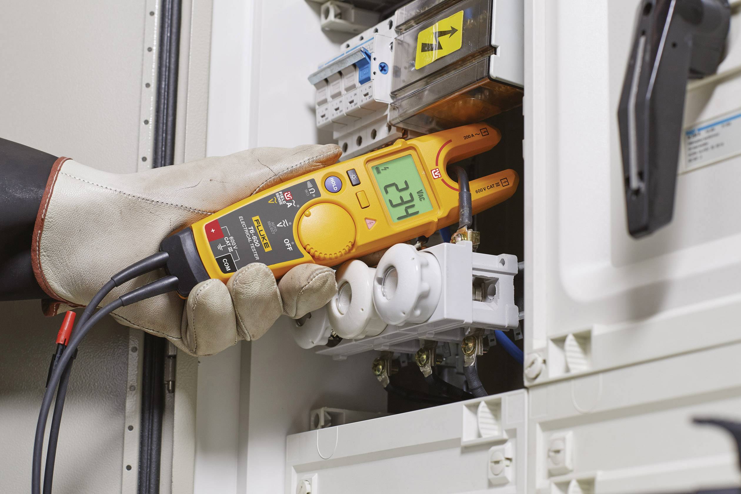 Een persoon met handschoenen meet met een multimeter de elektrische spanning in een schakelkast. Het display toont '625 V'.
