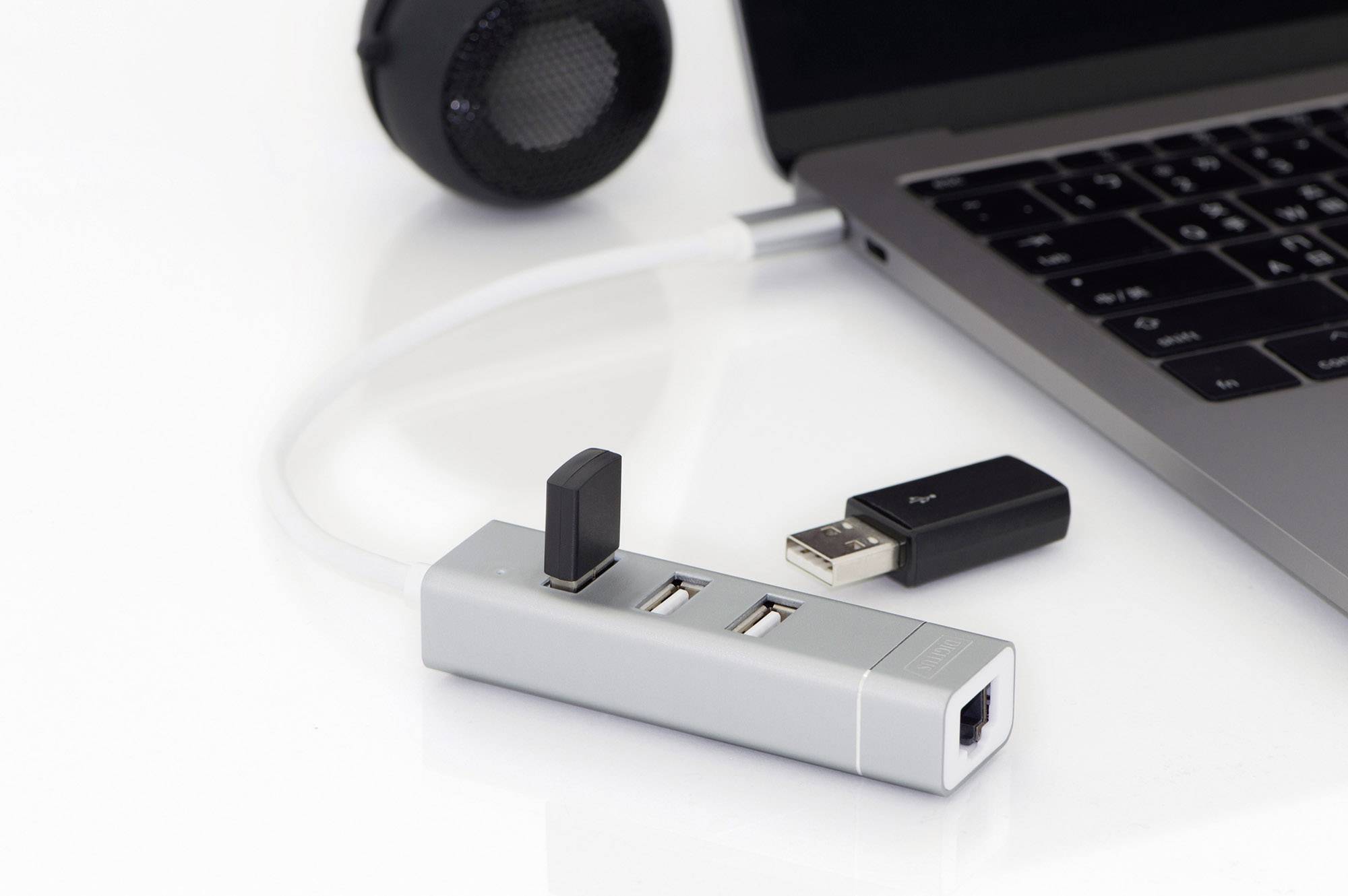 USB-hub met meerdere USB-sticks en een netwerkkabel, verbonden met een laptop, naast een luidspreker.
