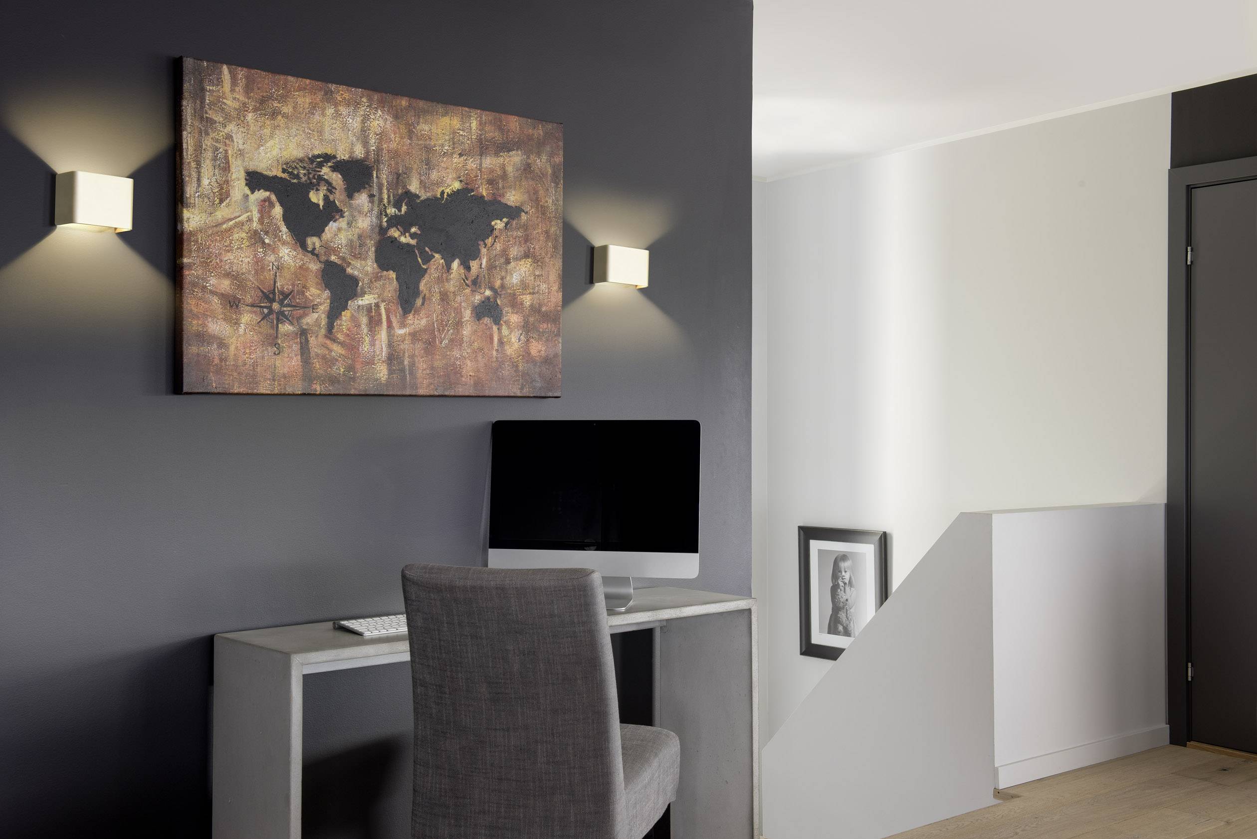 Werkplek met computer, wandkaart van de wereld, minimalistisch design, grijstinten, moderne inrichting.