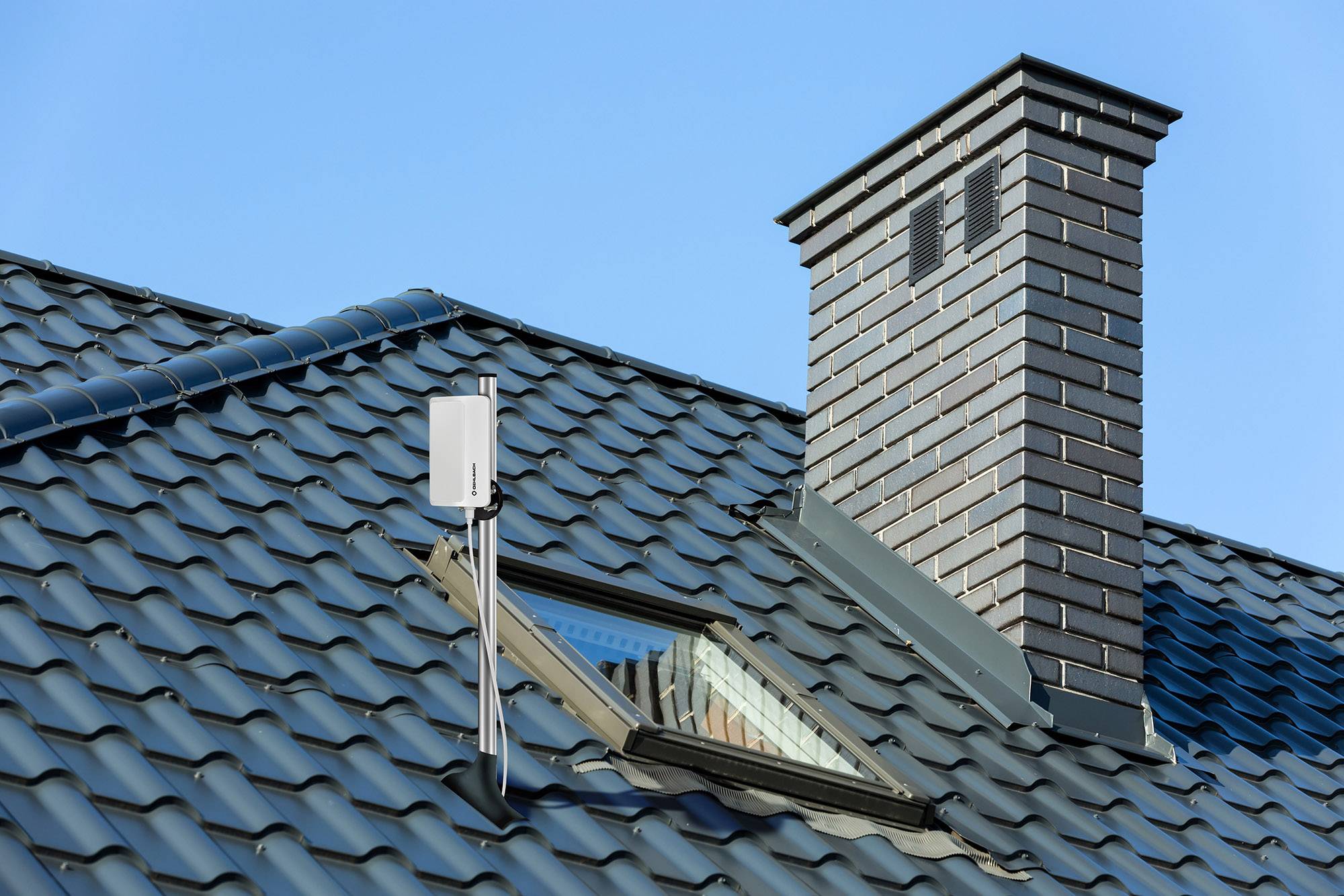 Een modern dak met zonnepanelen en een schoorsteen tegen een heldere hemel.