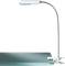 Een flexibele LED-leeslamp met klem, bevestigd aan een glazen plaat. Ideaal voor nauwkeurige verlichting tijdens het lezen of werken.
