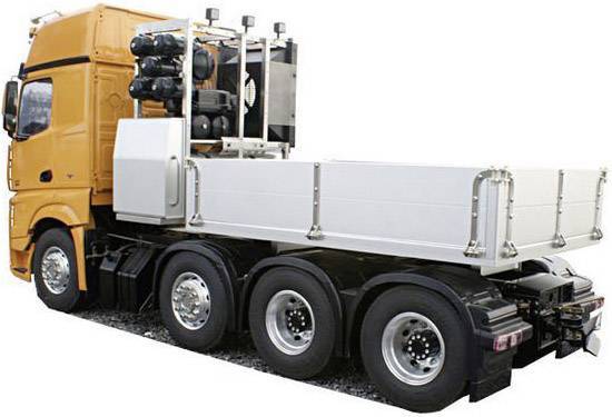 Een oranje vrachtwagen met drie assen en een witte laadruimte, van opzij gezien, staat geparkeerd op een weg.