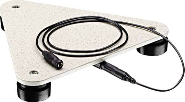 Een driehoekig, beige apparaat met een zwart snoer op pootjes. Het zou een sensor of een meetplatform kunnen zijn.