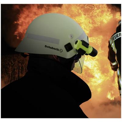 Een brandweerman met beschermhelm en camera staat voor een groot vuur.