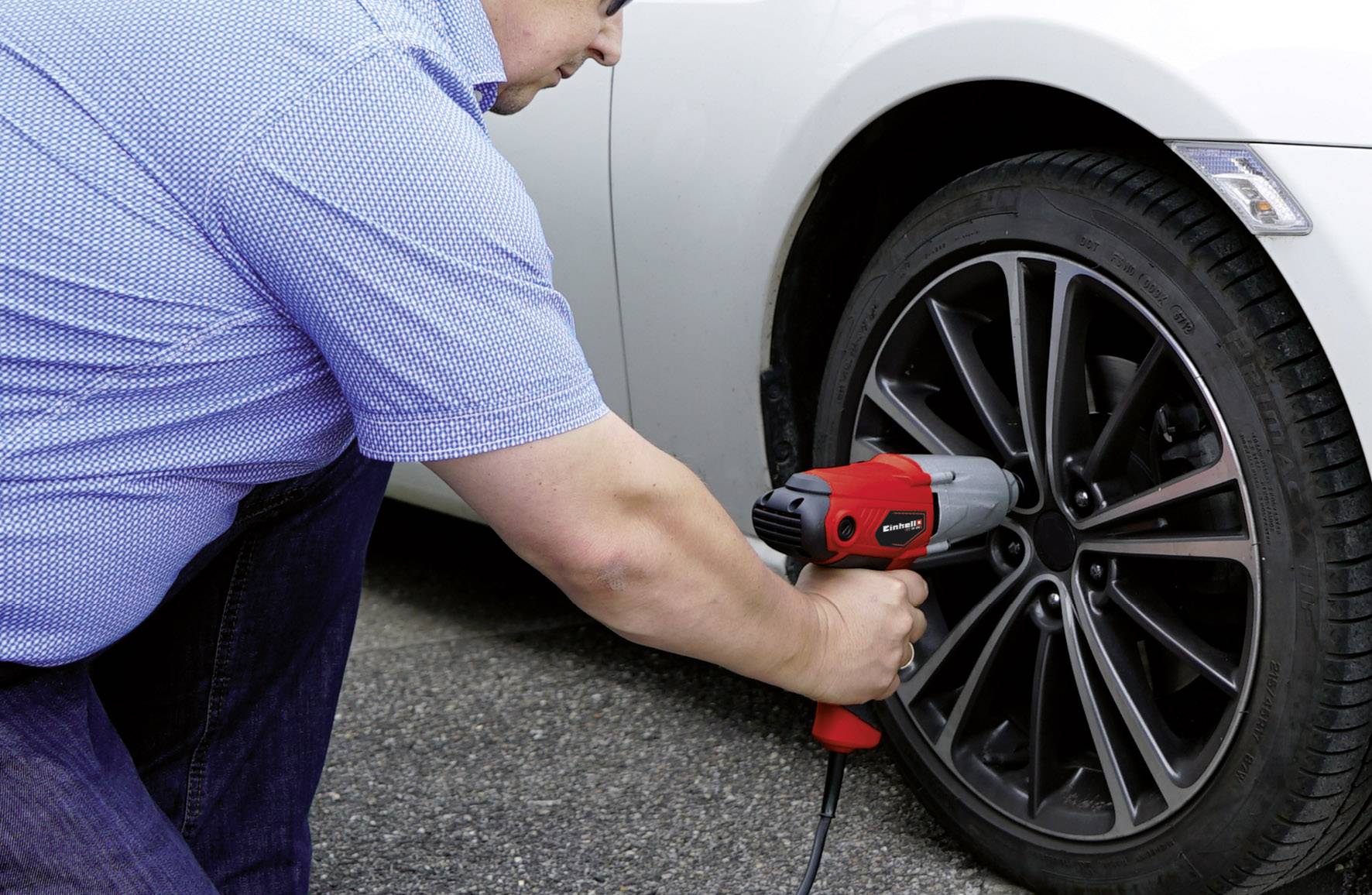 Een persoon verwisselt autobanden met een elektrische slagmoersleutel. De opname toont een close-up van het werk aan een autowiel.