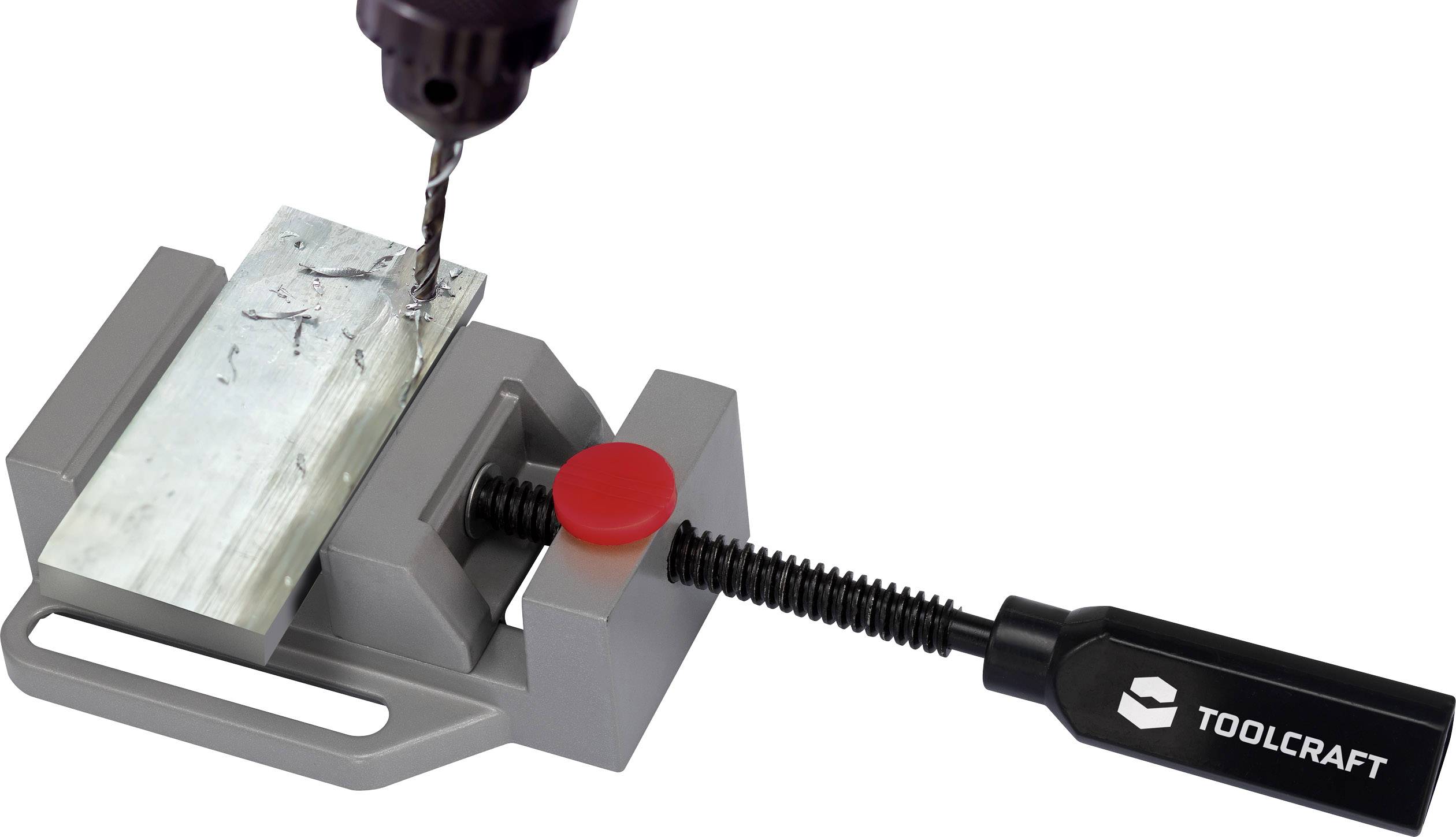 Een boormachine boort in een metalen stuk dat is vastgeklemd in een grijze bankschroef met een rode handgreep.