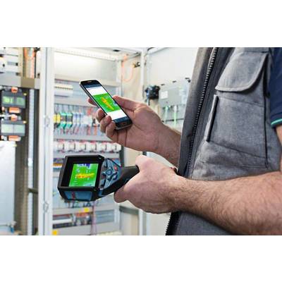 Een technicus houdt een digitaal diagnoseapparaat en een smartphone voor een open schakelkast en controleert elektrische installaties.