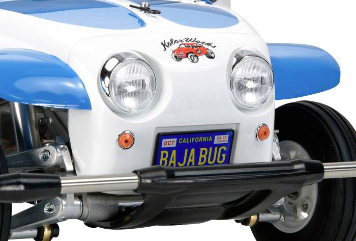 Close-up van een blauw en wit voertuig met een 'Bajabug'-kentekenplaat, opvallende koplampen en een kustwachtlogo.