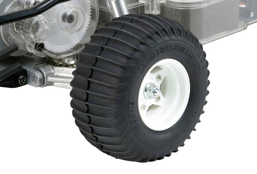 Zwart rubberen wiel met een witte velg op een machine, waarbij tandwielen en metalen onderdelen ook zichtbaar zijn.