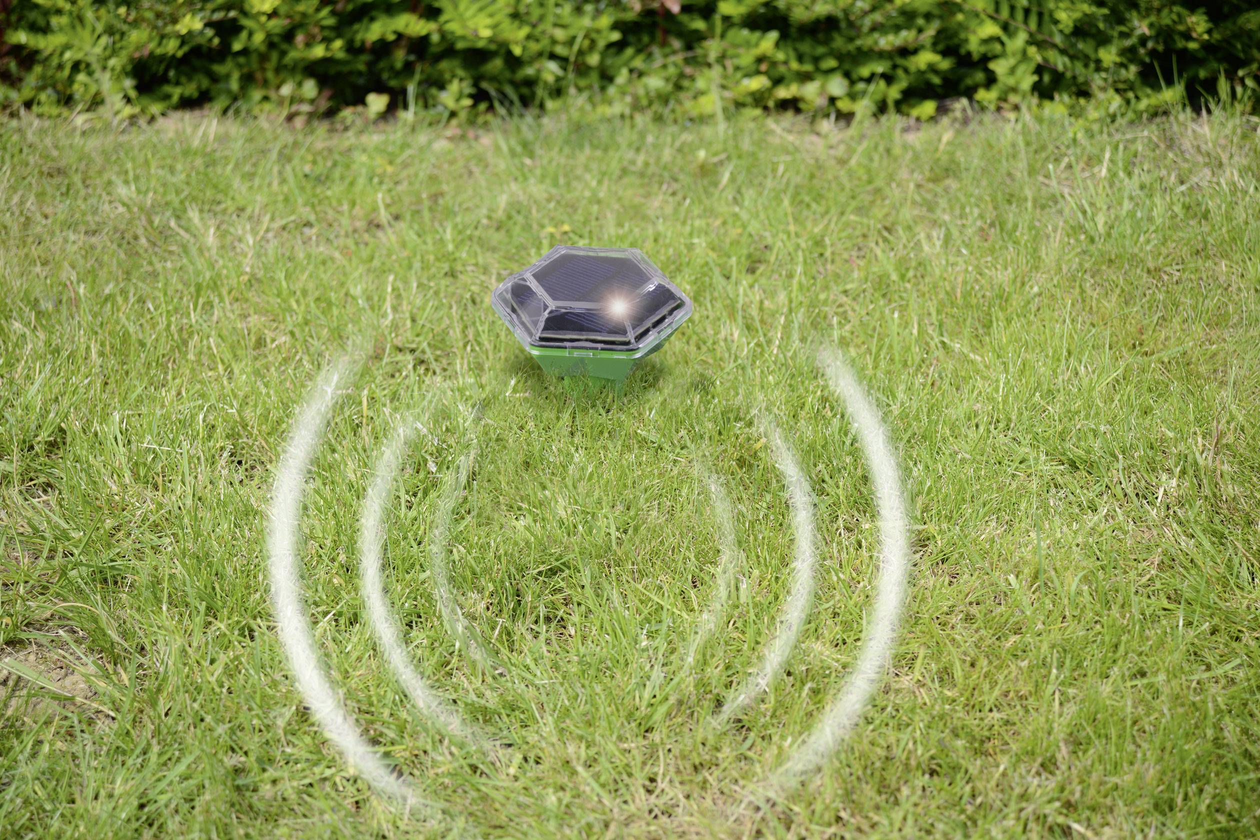 Een dierafweerapparaat met zonnepaneel op een grasveld zendt geluidsgolven uit om dieren op afstand te houden.