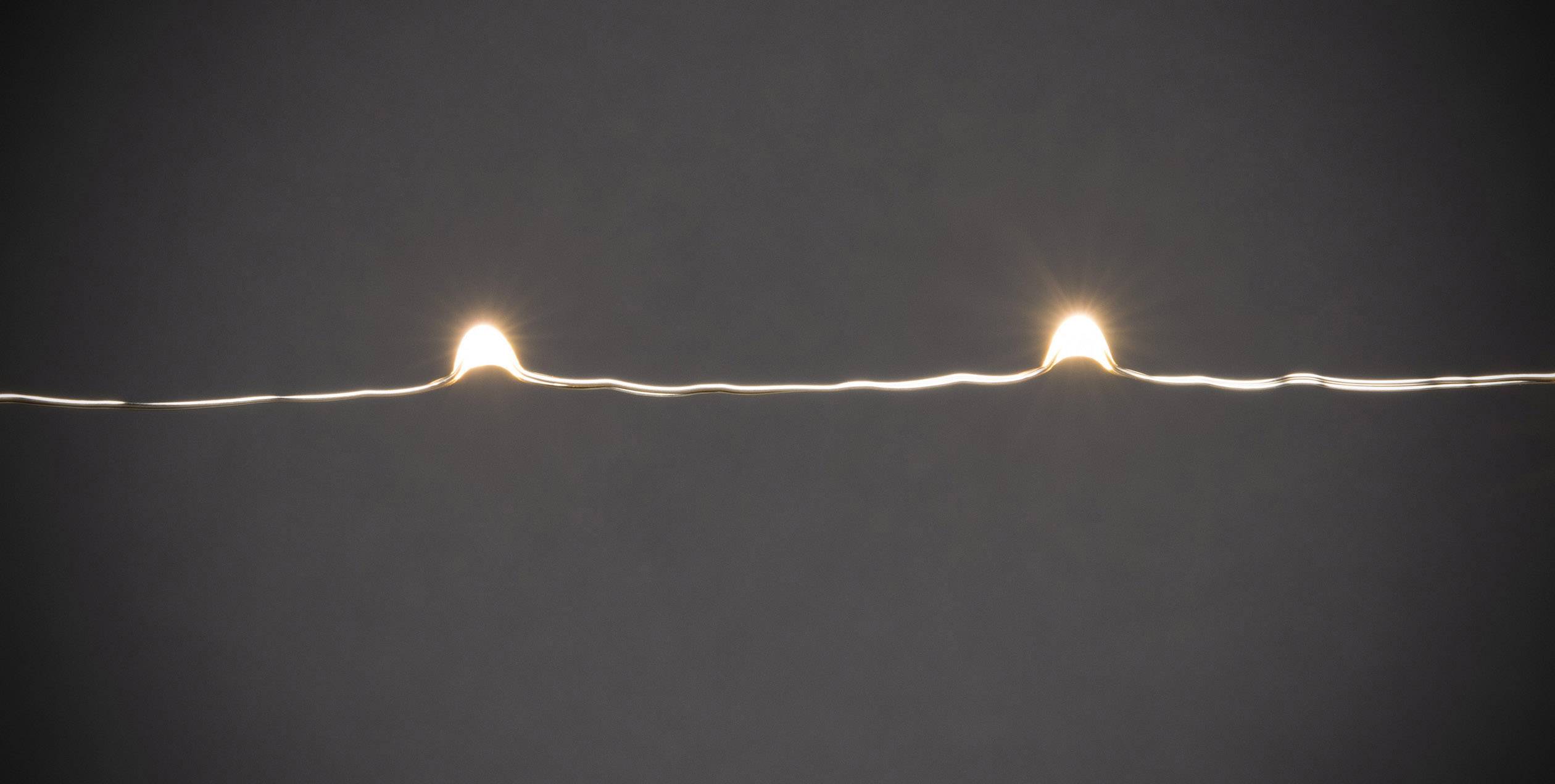 Twee kleine, lichtgevende puntjes op een donkere achtergrond, verbonden door een zwakke lichtstraal.