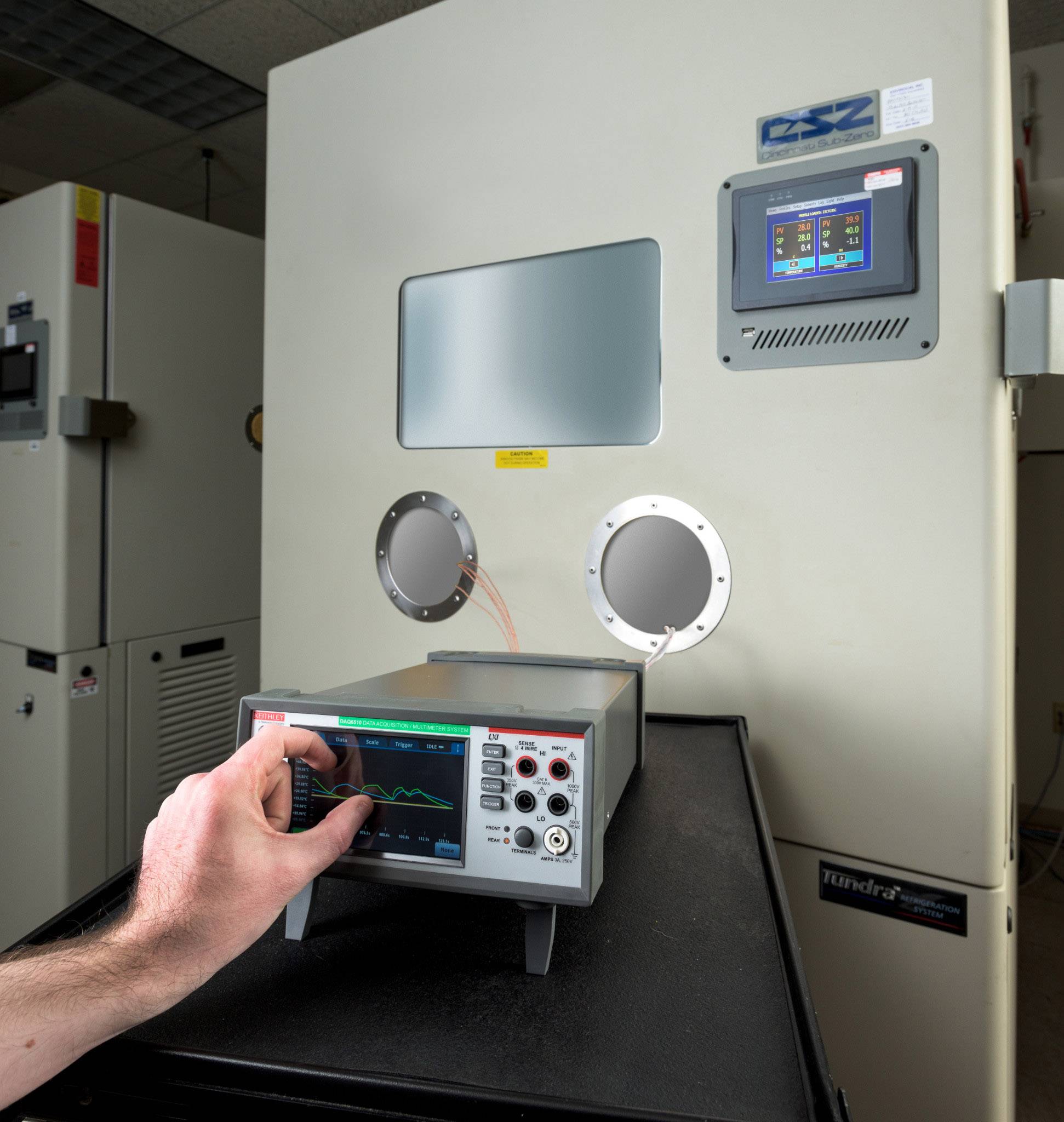 Een persoon bedient een technisch apparaat met een scherm dat is aangesloten op een grotere machine met een ronde opening.