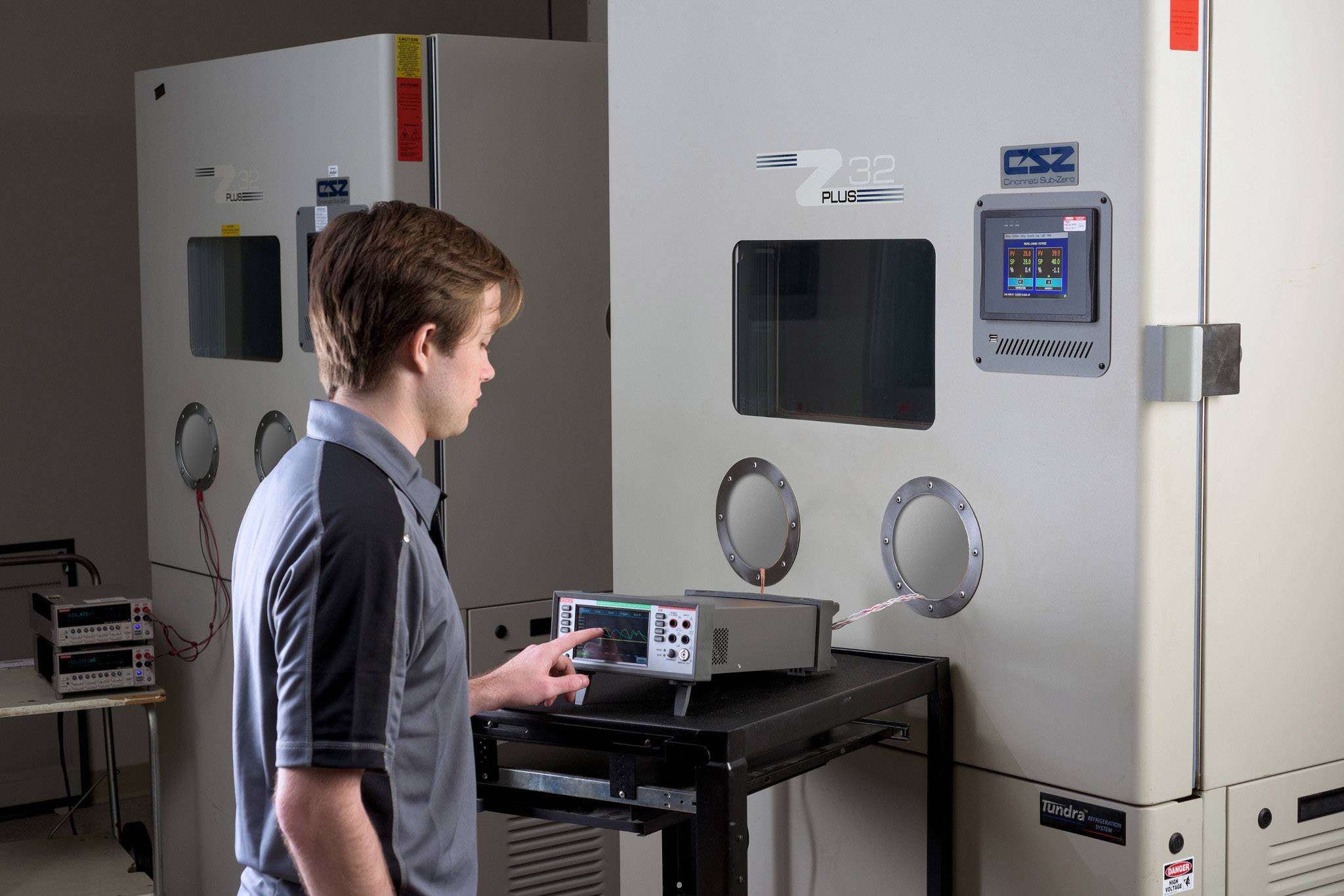 Een technicus controleert de instellingen op een elektronisch meetapparaat voor klimaatcellen om testomstandigheden te simuleren.