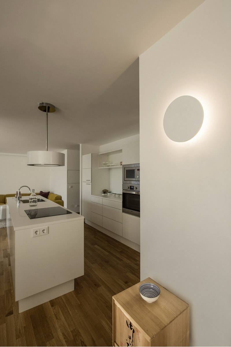 Moderne keuken met houten vloer, wit keukeneiland en hanglamp. Helder licht geeft de ruimte een uitnodigende sfeer.